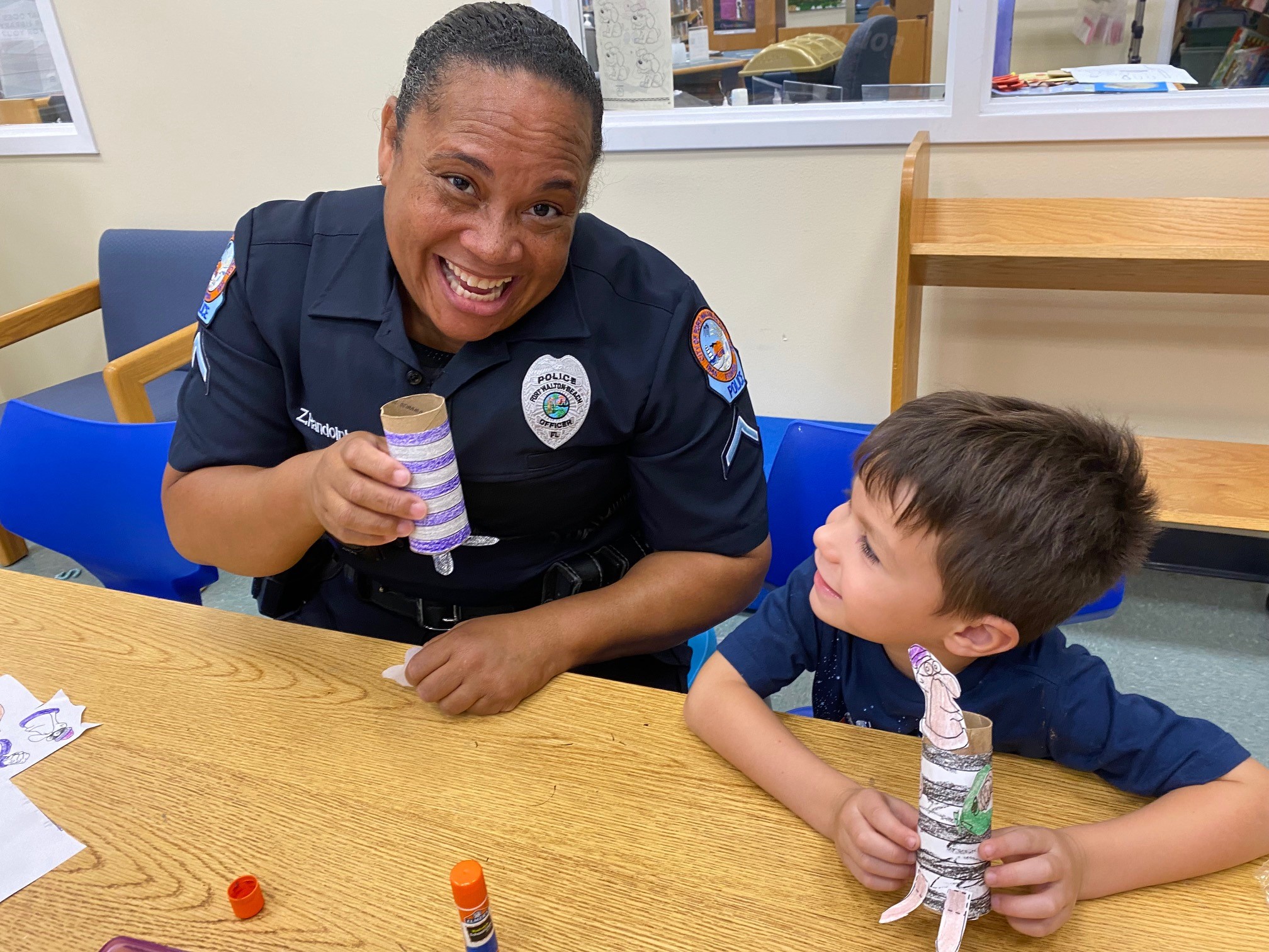 A cop shows off her craft while a child sits next to her and looks on. 