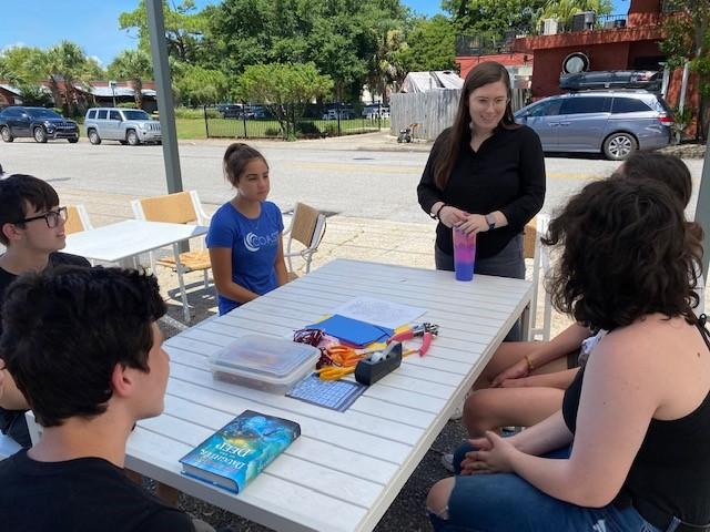 Teens sitting around a table outside.